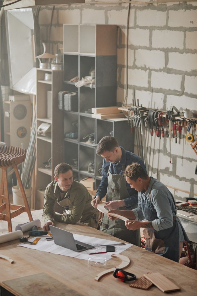 L’attribut alt de cette image est vide, son nom de fichier est plan-vertical-artisans-modernes-concevant-meubles-artisanaux-dans-atelier-charpentiers-683x1024.jpg.